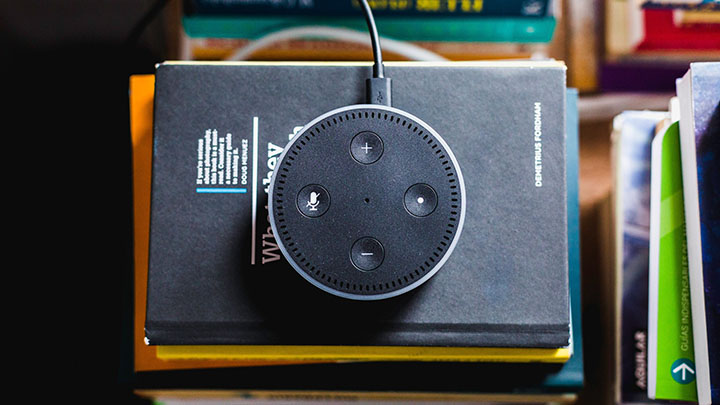 A photo of alexa virtual assistant device on top of pile of books