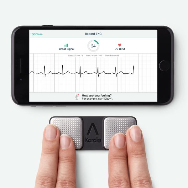 A smartphone showing heart rate reading from an app connected to a device shown underneath with four fingers of each hand on it