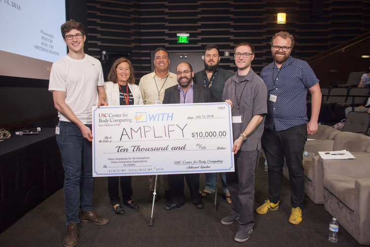 Executive Director of the USC Center for Body Computing Dr. Leslie Saxon, and other Hackathon judges, present the $10,000 check to the winners, Team Amplify.